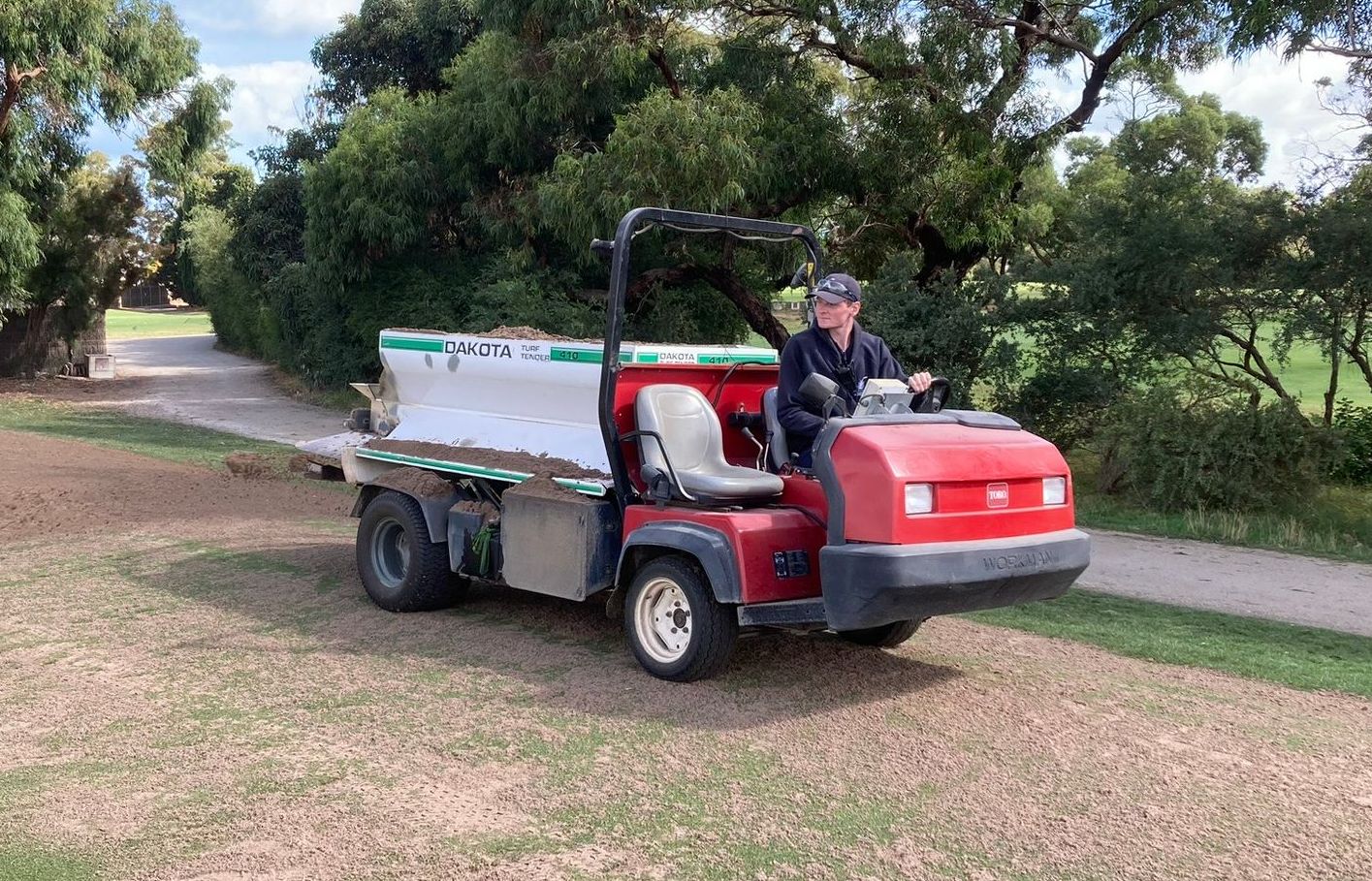 a man is driving a red truck down a dirt road .