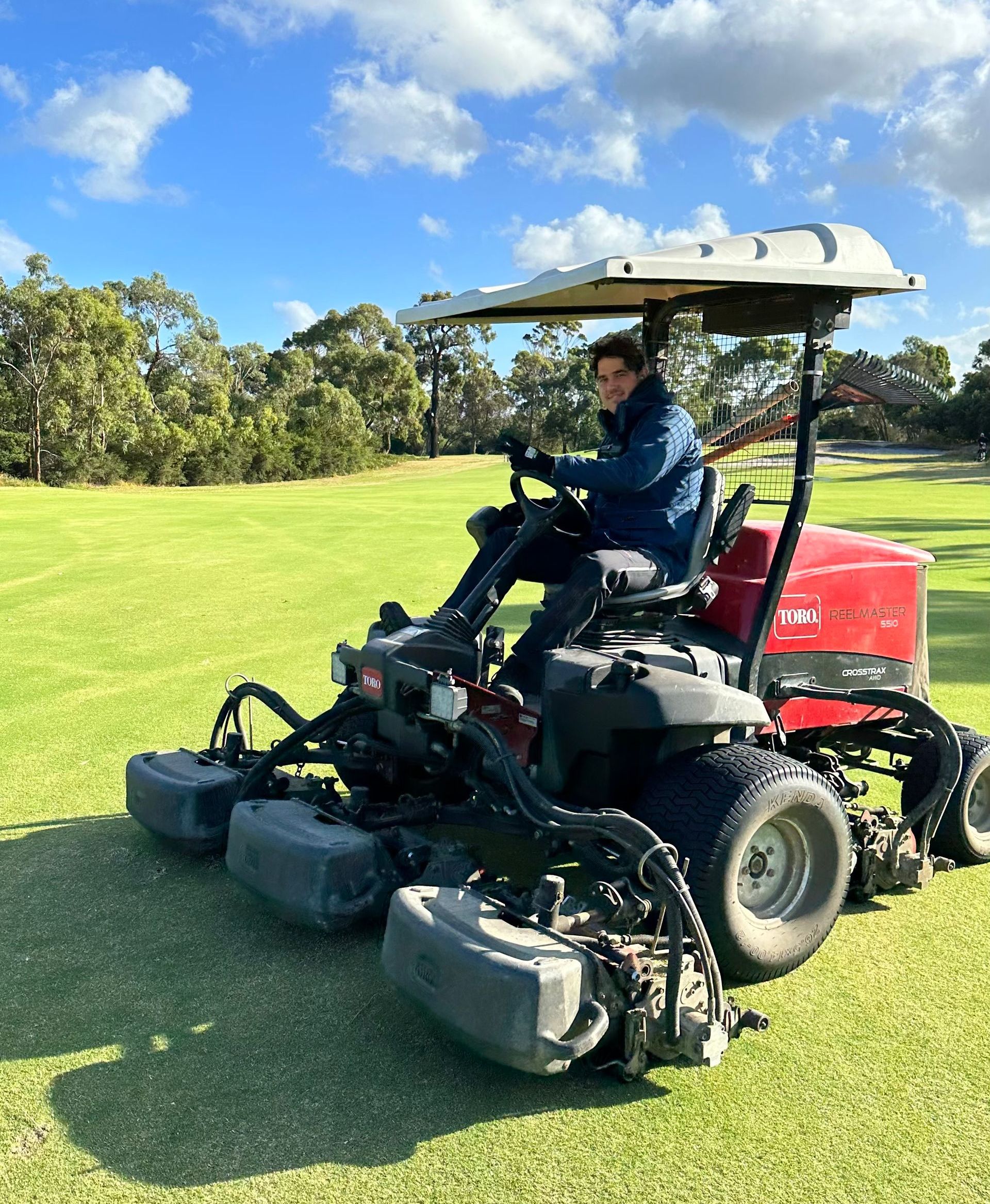 a man is riding a lawn mower on a golf course .
