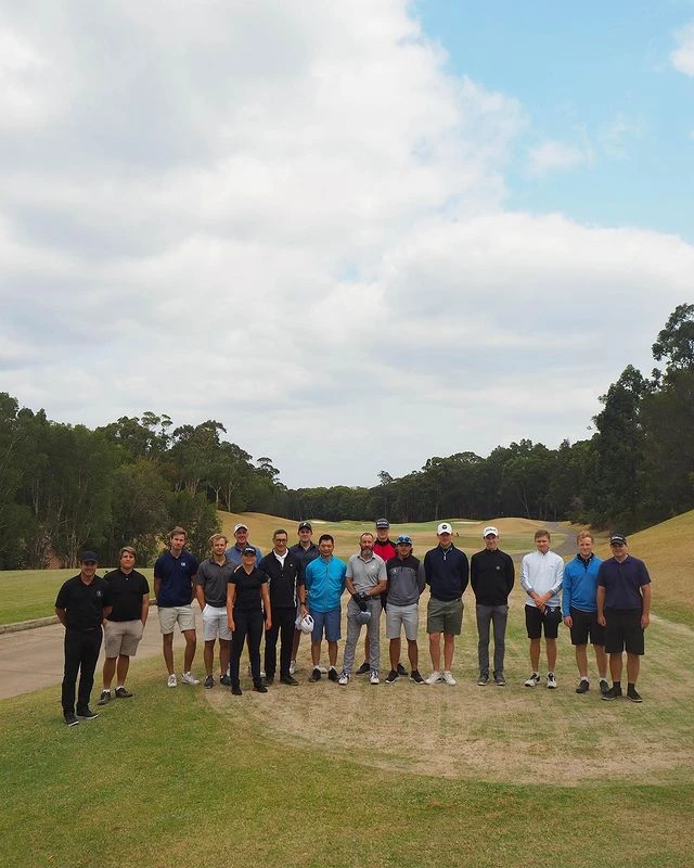 a group of men are posing for a picture on a golf course