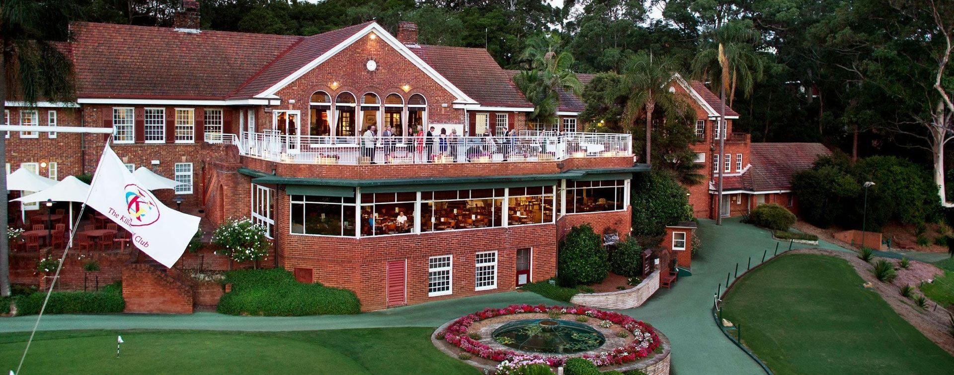 An aerial view of a large brick house with a golf course in front of it